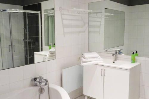y baño con bañera, lavabo y espejo. en Les Jasmins 8 pers Piscine commune calme et confort, en Saint-Gilles