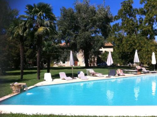 une piscine avec chaises longues et parasols dans l'établissement Les Jasmins 8 pers Piscine commune calme et confort, à Saint-Gilles
