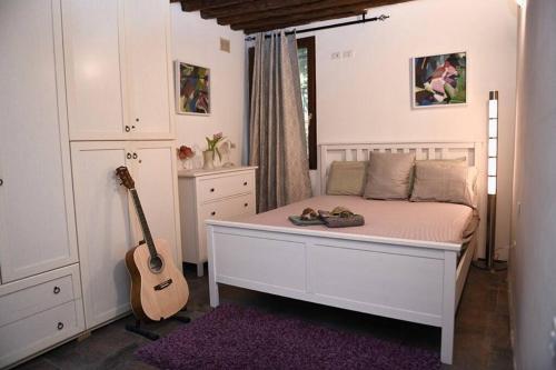 una camera con un letto bianco e una chitarra di Grace Apartment in Venice a Venezia