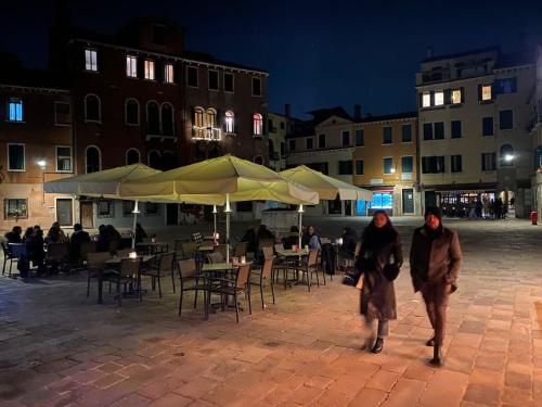 Grace Apartment in Venice في البندقية: سيدتان تتمشيان في شارع في الليل