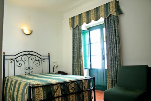 a bedroom with a bed and a chair and a window at Hotel Santa Comba in Moura