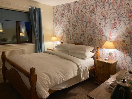 Schlafzimmer mit einem Bett mit Blumentapete in der Unterkunft Laundimer House in Corby