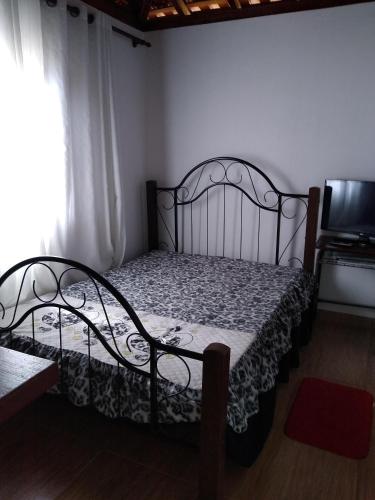 1 dormitorio con 1 cama de metal en una habitación en Quitinete aconchegante em Sobradinho, São Tomé das Letras, en São Thomé das Letras