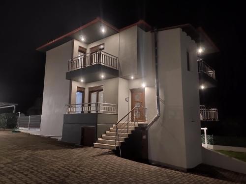 a white building with stairs and a balcony at night at Kashmir Luxury Apartments in Neos Marmaras