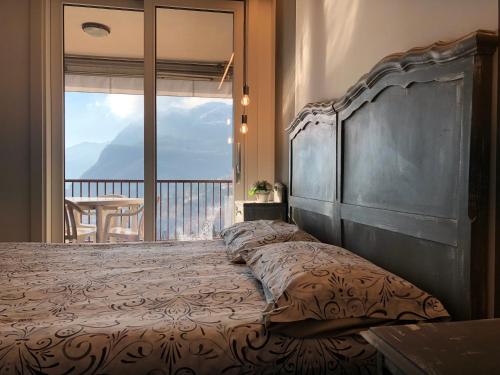 a bedroom with a large bed with a large window at Appartamento vista lago Le Terrazze piscina-tennis-parking in Menaggio