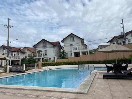 a swimming pool with chairs and houses in the background at Cozy staycation villa in Quirino Hwy, QC in Manila