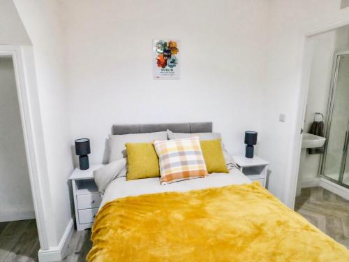 a bedroom with a bed with a yellow blanket on it at Port Apartment 1 in Holyhead