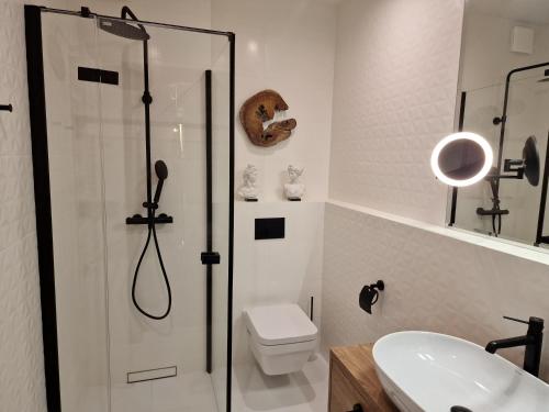 een badkamer met een douche, een toilet en een wastafel bij WAVE Apartament Słońce Toskanii in Międzyzdroje