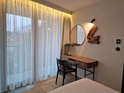 een slaapkamer met een bureau, een spiegel en een raam bij WAVE Apartament Słońce Toskanii in Międzyzdroje