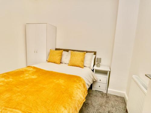 a bedroom with a bed with a yellow blanket on it at Port Apartment 2 in Holyhead