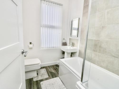ein weißes Bad mit einem Waschbecken und einem WC in der Unterkunft Port Apartment 2 in Holyhead