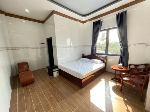 a bedroom with a bed and a table and a window at Nhà nghỉ Quỳnh Như in Cao Lãnh