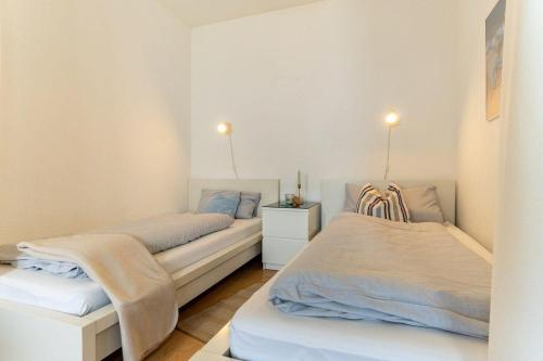 1 dormitorio con 2 camas y mesita de noche en Vier-Jahreszeiten-Haus-IV-Wohnung-4, en Großenbrode