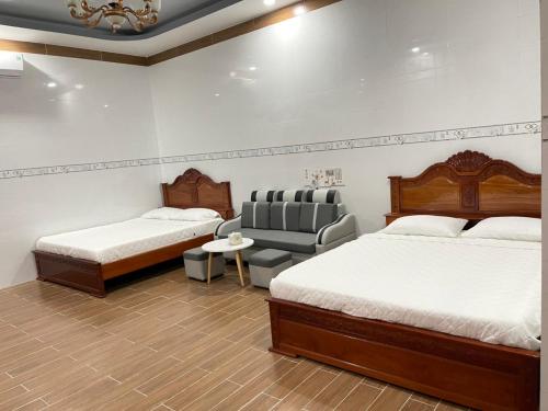 a hotel room with two beds and a chair at Nhà nghỉ Quỳnh Như in Cao Lãnh