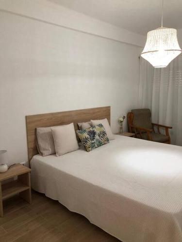 a bedroom with a large white bed and a chair at Apartamento T2 Montegordo a 500 m da praia in Monte Gordo