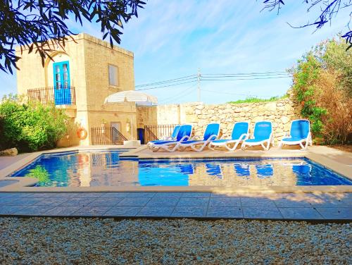 um grupo de cadeiras azuis sentadas numa piscina em Ta’ Peppi Farmhouse em Qala