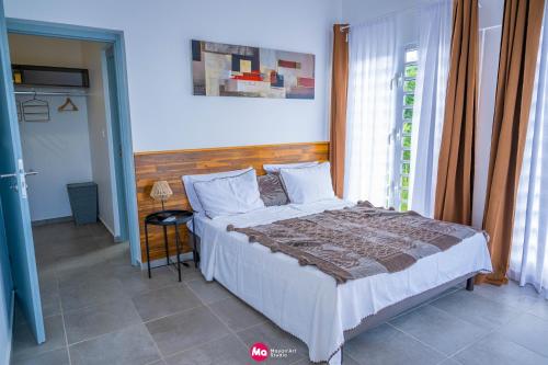 ein Schlafzimmer mit einem Bett in einem Zimmer mit einem Fenster in der Unterkunft TSINGONI VILLAGE Meublé de Tourisme in Tsingoni