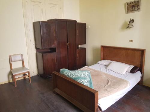 a bedroom with a bed and a cabinet and a chair at Clement's House Hostel in Alexandria