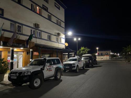 a group of vehicles parked on a street at night at Hotel Dubai in Tan-Tan Plage