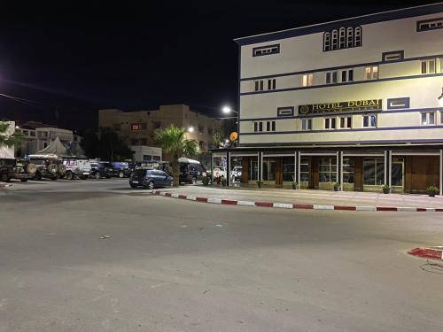 a building with a car parked in front of a street at Hotel Dubai in Tan-Tan Plage