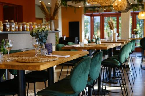 a row of tables in a restaurant with green chairs at Quintessia in Orvault