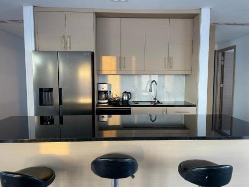 a kitchen with black stools and a stainless steel refrigerator at Modern villa - in Golden Circle - Gullfoss Geysir Þingvöllur - Freyjustíg 13, 805 Selfoss in Búrfell