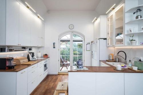 a kitchen with white cabinets and a large window at Apartament Krokusowa in Rumia