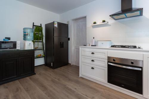 a kitchen with white cabinets and a black refrigerator at Casa Solcor Boutique Bed & Breakfast in San Pedro de Atacama