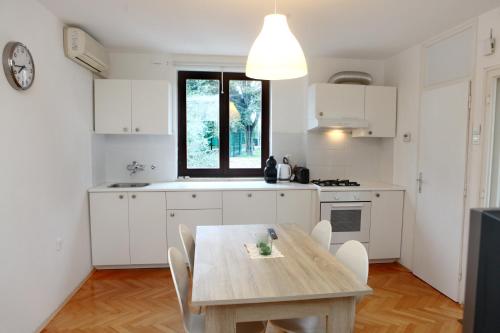 een keuken met een houten tafel en witte kasten bij Warm and Comfy Piran Apartment with Parking! in Piran
