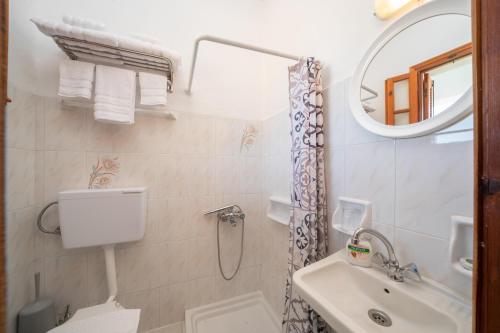 a bathroom with a sink and a toilet and a mirror at Myrtos View Apartments in Anomeriá