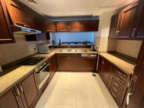 uma pequena cozinha com armários de madeira e um lavatório em شقق فخامة المارينا Grandeur Marina Apartments em King Abdullah Economic City