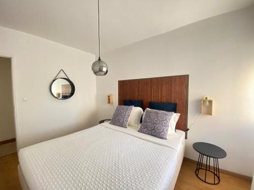 a bedroom with a white bed and a table at Central Station Apartment in Setúbal
