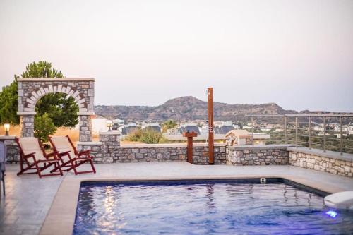 a swimming pool on a patio with two chairs next to at Des & Coo Luxury Villa with Private Pool in Faliraki