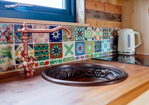 a sink in a kitchen with colorful tiles at Laundimer House in Corby