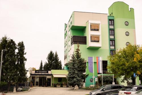 MC Hotel في Žalec: مبنى أخضر فيه سيارات متوقفة أمامه