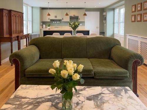 a living room with a green couch and a table with flowers at Converted Victorian Coach House with Hot Tub in Stewartstown
