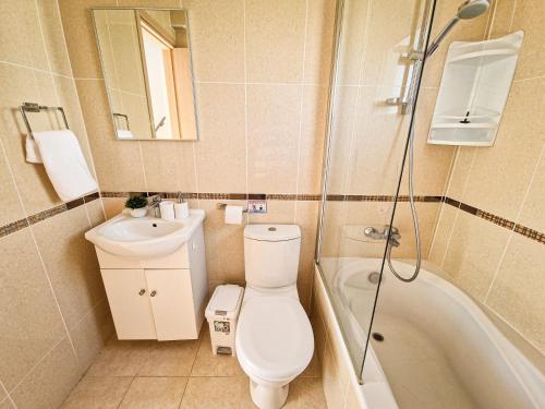 a bathroom with a toilet and a sink and a tub at Nissi beach villa Oleandra in Ayia Napa
