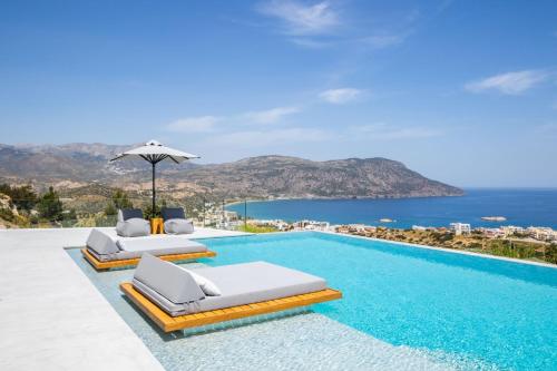a pool with two lounge chairs and an umbrella at ISTIA LUXURY VILLAS in Karpathos Town