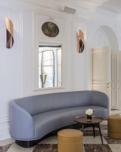 a living room with a blue couch and a table at Hôtel Vernet Champs Elysées Paris in Paris