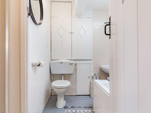 La salle de bains blanche est pourvue de toilettes et d'un lavabo. dans l'établissement West Lane Cottage, à Delabole