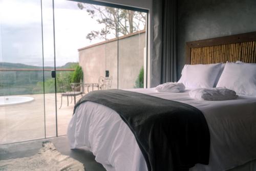 a bedroom with a large bed and a large window at Pousada Monttana - By UP Hotel in Lavras Novas