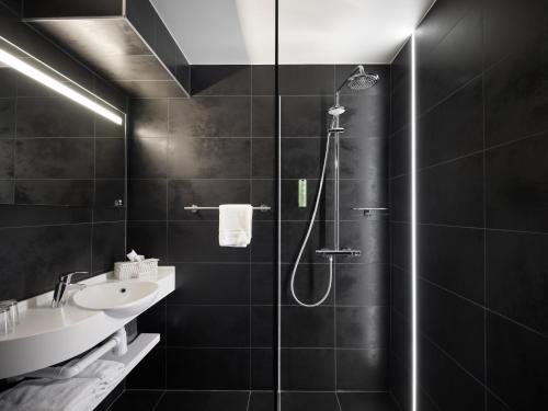 uma casa de banho preta com um chuveiro e um lavatório em Le 24 Hotel em Spa