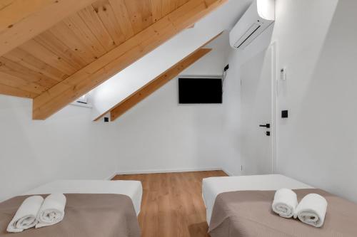 two beds in a white room with wooden ceilings at Apartment Vise - Old Town Center, Stone Terrace in Omiš