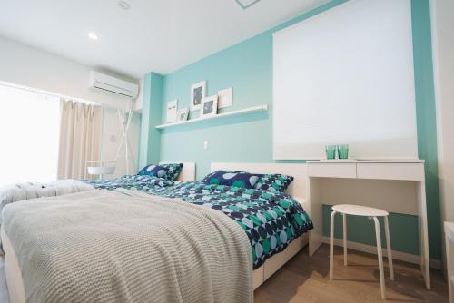 a bedroom with blue walls and a bed and a desk at Shinjuku Mermaid Apartment in Tokyo