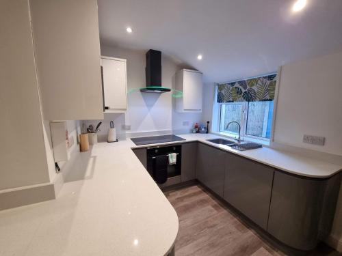 eine weiße Küche mit einem Waschbecken und einer Arbeitsplatte in der Unterkunft Well Cottage by Cliftonvalley Apartments in Bristol