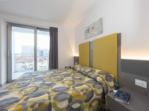 een slaapkamer met een bed en een groot raam bij Nashira Apartments in Lignano Sabbiadoro