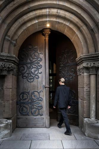 a man walking into a large wooden door at HOTEL & SPA Goldene Rose in Dinkelsbühl