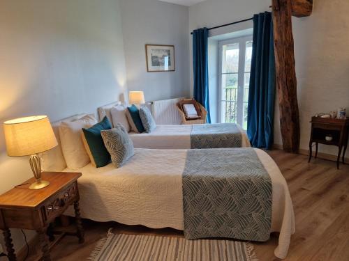 Un dormitorio con dos camas y una mesa con lámpara. en Ferme d'Orsonville, en Villiers-en-Bière