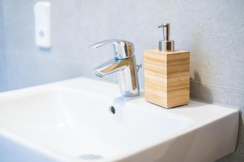 a bathroom sink with a faucet and a wooden holder at FULL HOUSE 3 Bedroom Apartment Halle NH14 in Halle an der Saale