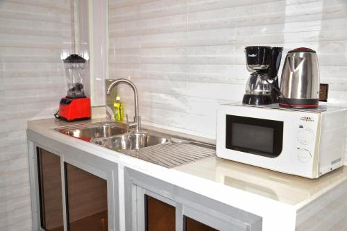 a kitchen counter with a microwave and a sink at Tulsa Home - Douala - Bonamoussadi - Wifi - Canal+ in Douala